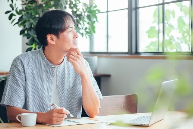 窓の外を見つめる考える男性