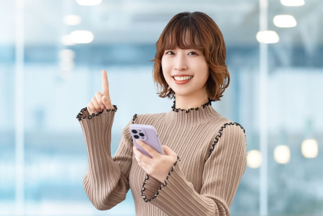 スマホを見る指を指す女性